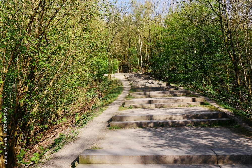 Obraz premium Interesting shadows cast by the trees to the concrete stairs at the beginning of the ascent to Beckstrasse heap in Bottrop Germany, 72 meters high and rises to about 113.8 meter