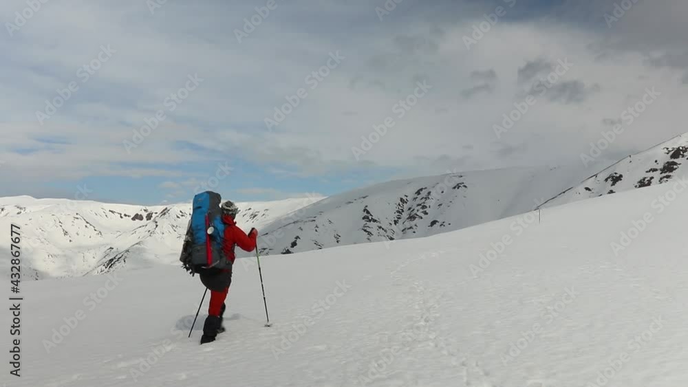 Hiker walks on snow in the high mountains during winter