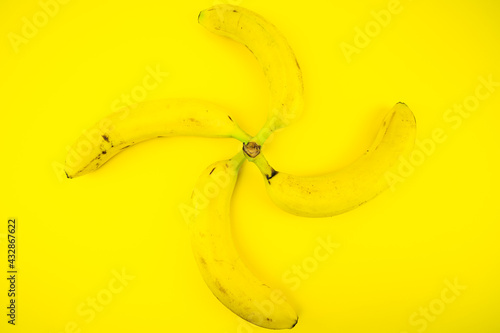 Quattro banane su sfondo giallo formano un elica photo