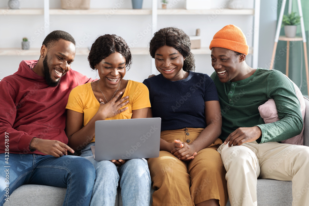 Happy black friends men and women using laptop, home interior Happy black friends men and women using laptop, home interior