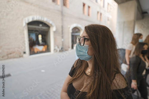 Ritratto di una ragazza sorridente con gli occhiali e la mascherina durante una giornata di svago in giro per la città di Ferrara photo