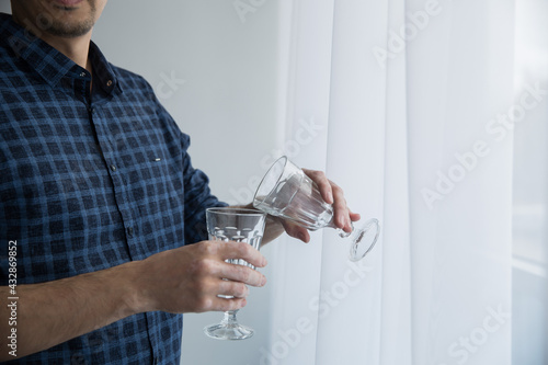 the man is holding empty wine glasses and his hands are stained with vitiligo.