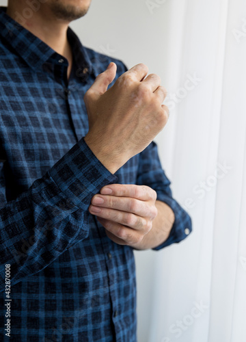 vitiligo man's hand fastens the sleeve of his shirt