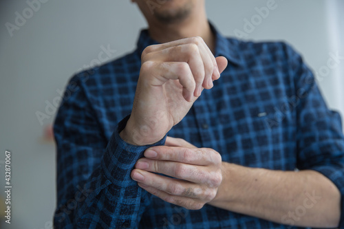 a man's vitiligo arm fastens the sleeve on the shirt photo from the front