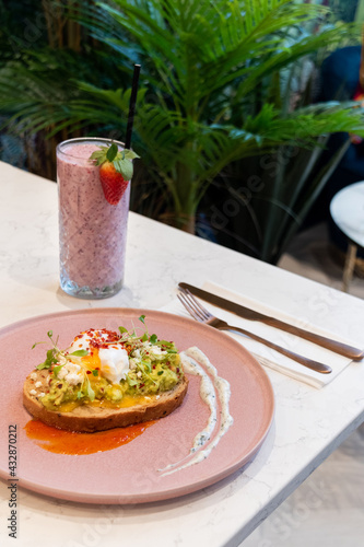 Healthy breakfast avocado toast with poached egg and strawberry smoothie