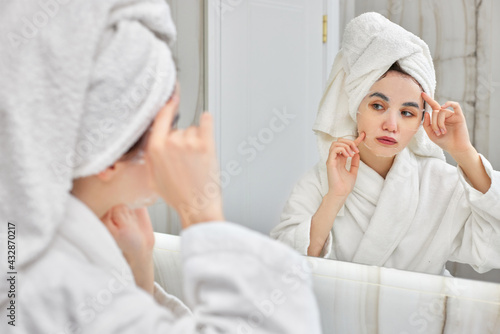 woman in white bathrobe in front of mirror in bathroom