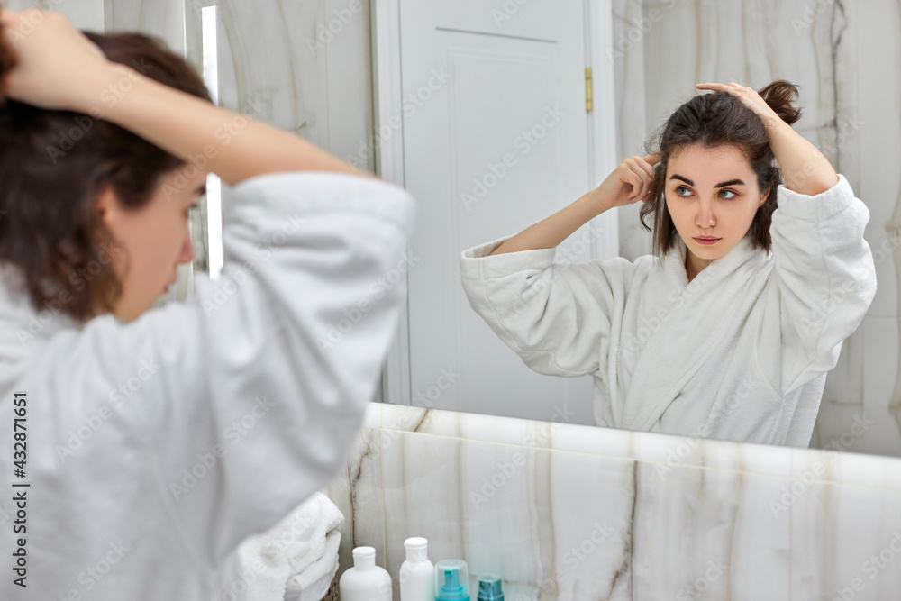 woman using a hair straightener in bathroom. woman using a hair straightener in bathroom.