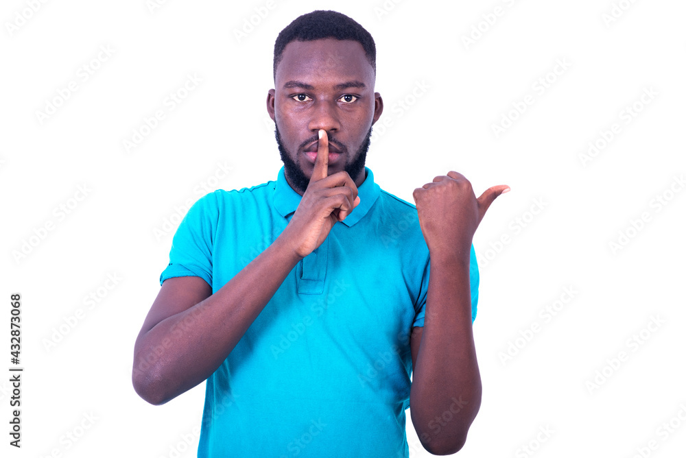 young man asking to be calm with finger on lips pointing with finger to the side. young man asking to be calm with finger on lips pointing with finger to the side.