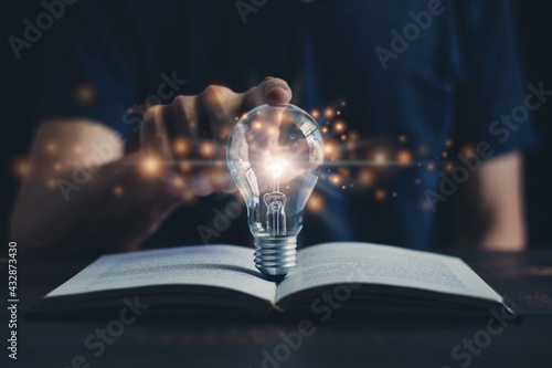 Glowing light bulb and book or text book with futuristic icon. Self learning or education knowledge and business studying concept. Idea of learning online class or e-learning at home. photo