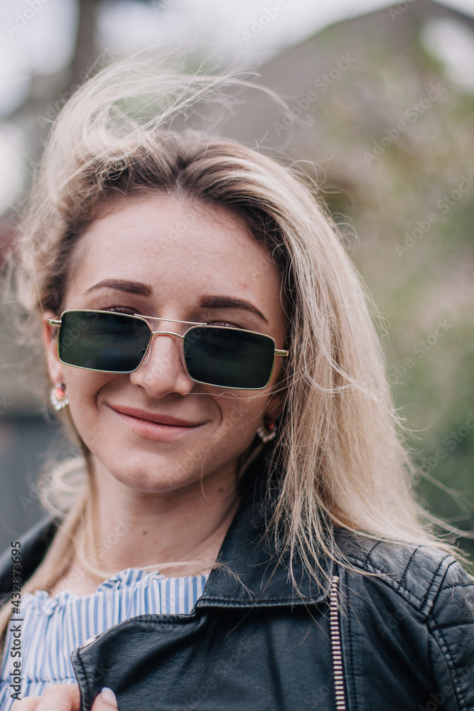 Young blonde in leather jacket and sunglasses posing in the street Young blonde in leather jacket and sunglasses posing in the street