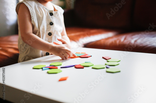 child toddler plays with wooden mosaic on white table, earlier kid development and children's games, child plays with a puzzle close-up, toning