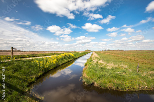 Fényképezés View over a Dutch landscape with a canal, grass, blue sky, white clouds