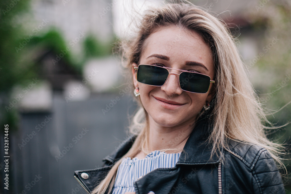 Young blonde in leather jacket and sunglasses posing in the street Young blonde in leather jacket and sunglasses posing in the street