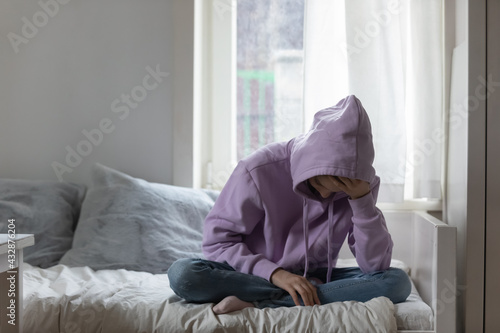 Fotografija Unhappy young adolescent 12s kid girl sitting on comfortable bed, feeling exhausted or depressed alone at home