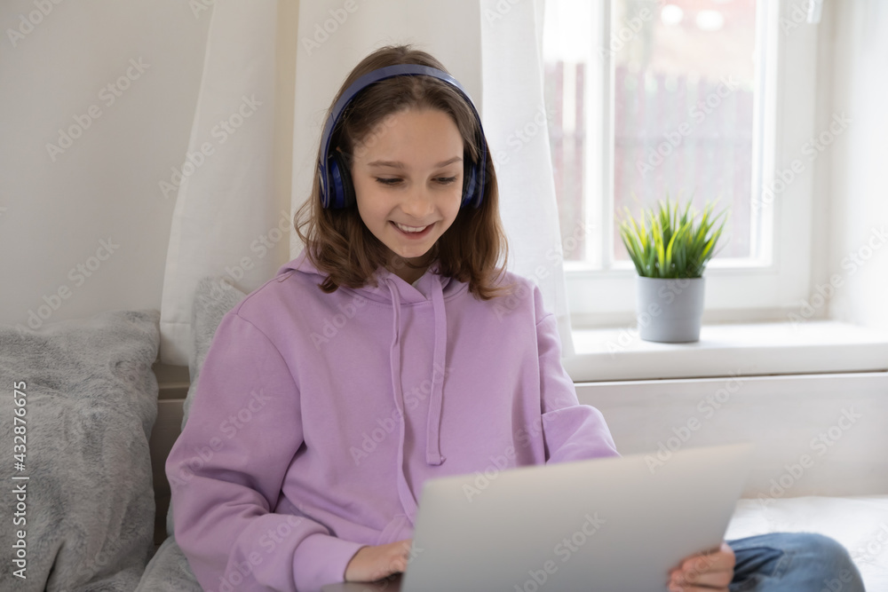 Smiling Z generation teenage girl in comfort wear enjoying playing online video game with friends distantly, entertaining alone in own room. Happy schoolgirl in headphones watching educational lecture Smiling Z generation teenage girl in comfort wear enjoying playing online video game with friends distantly, entertaining alone in own room. Happy schoolgirl in headphones watching educational lecture