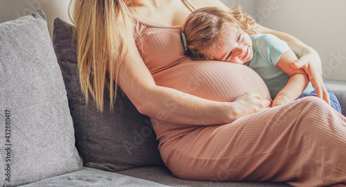 Little baby girl relaxing on mom's pregnant belly - Pregnant mother with a toddler - Family concept