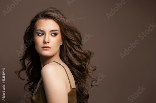 Attractive young woman with long perfect brown hairstyle on brown background