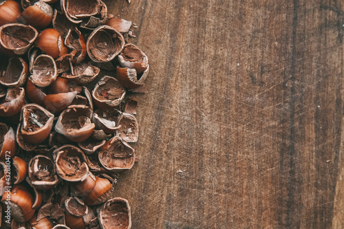 Hazelnut shells lie on a wooden table. Copy space