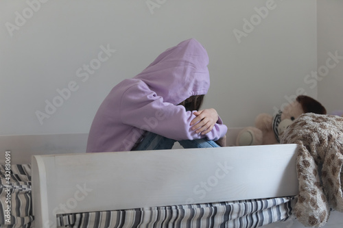 Photography Frustrated young teenager girl wearing hood on head cuddling knees, suffering from negative thoughts, lack of support, bullying or having depressive mood, adolescent psychological problems concept