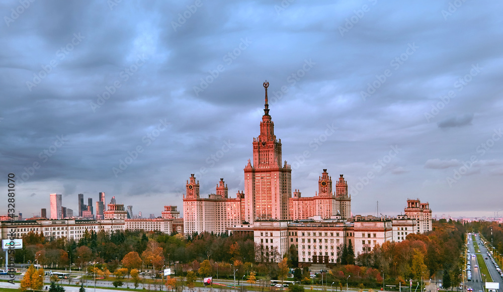 Fototapeta premium Aerial panoramic view of sunset campus buildings of famous Moscow university under dramatic cloudy sky in autumn