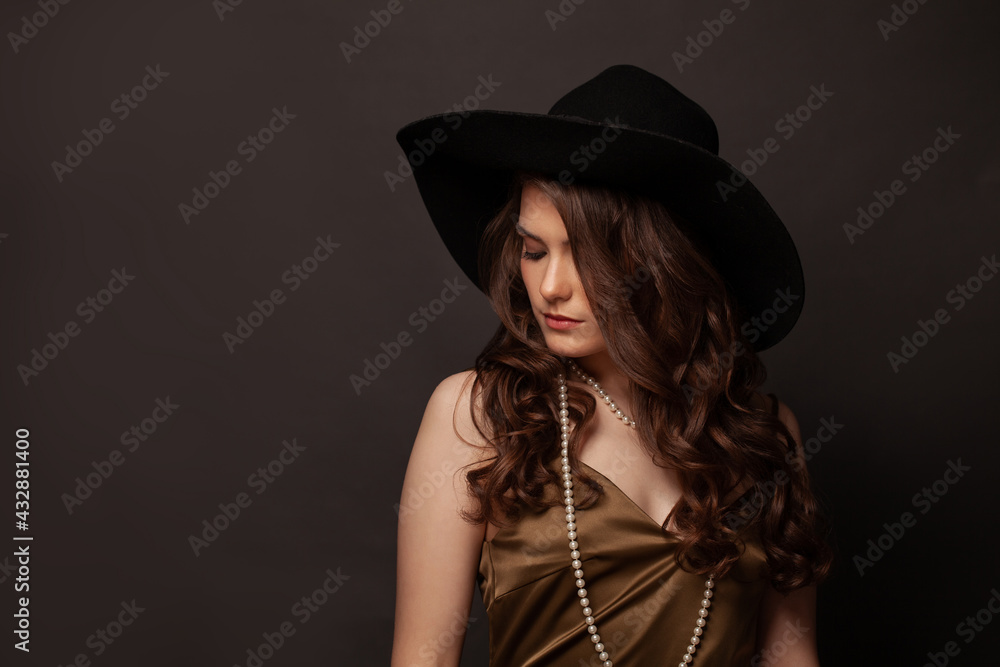 Fashionable brunette woman in black hat and pearls necklace on dark background Fashionable brunette woman in black hat and pearls necklace on dark background