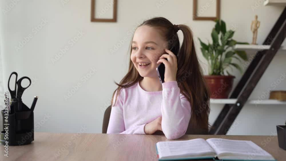 Caucasian girl sitting at her desk talking on a mobile phone, using a gadget and a network. A young lady communicates with her friend on her cell, discussing her studies and homework. Caucasian girl sitting at her desk talking on a mobile phone, using a gadget and a network. A young lady communicates with her friend on her cell, discussing her studies and homework.