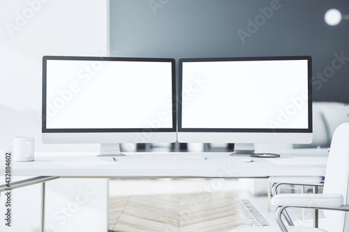 Blank white modern computer monitors as a part of stylish work place with light table in sunny room on home interior background. 3D rendering, mockup photo