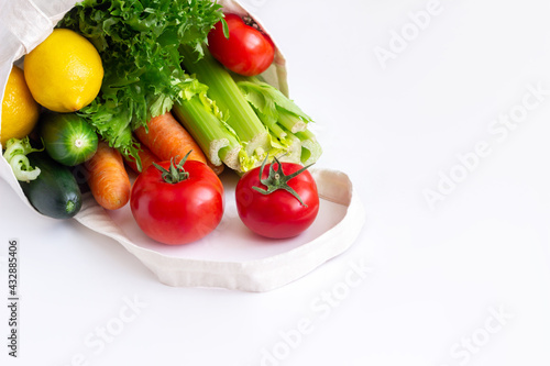 Fresh raw vegetables and fruit. Tomatoes, cucumbers, carrots, celery, green lettuce, lemon from the store in fabric natural eco reusable linen bag isolated on a white background. Food Vegan Shopping