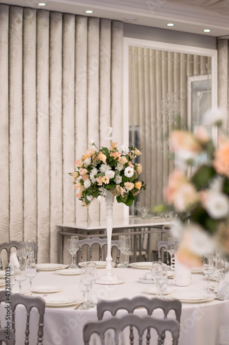 Fototapeta Naklejka Na Ścianę i Meble -  Centerpiece made of green leaves and fresh flowers stands on the dinner table. Wedding day. Fresh flowers decorations.