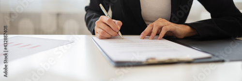 Businesswoman signing a document or application form in a folder photo