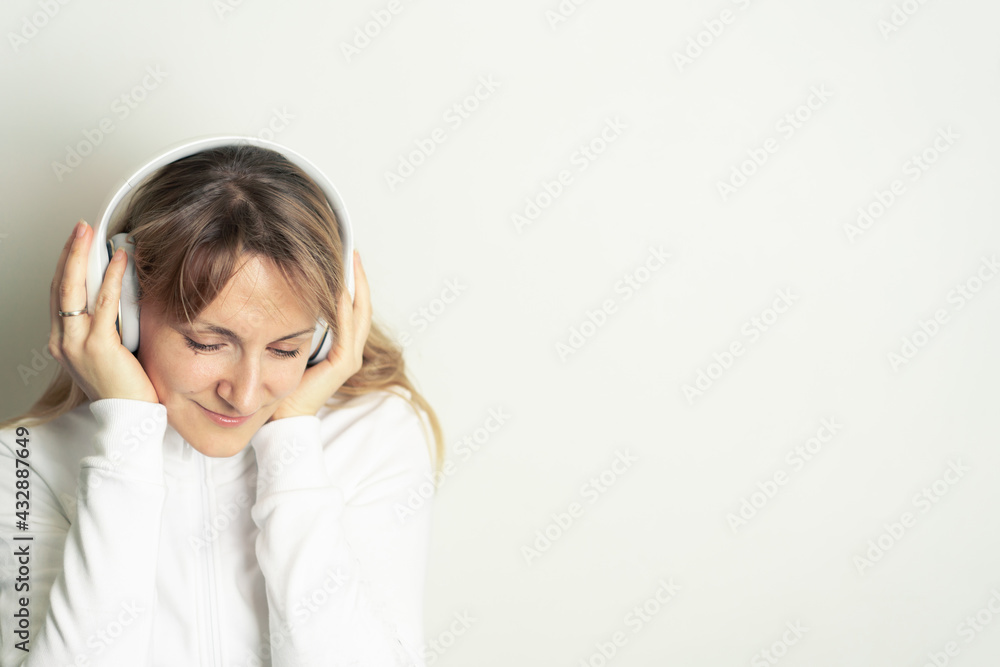Portrait of smiling pretty woman enjoying music with white headphones on white background Portrait of smiling pretty woman enjoying music with white headphones on white background
