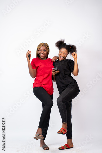 two attractive young african women looking excited and happy about something, advertising concept, standing against a white background