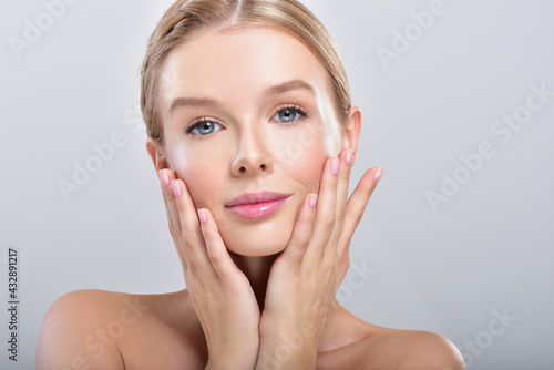 Beautiful face of young adult woman with clean fresh skin.  Fashion Model Girl Face. Perfect Skin. Professional Makeup. Fashion shiny highlighter on skin, sexy gloss lips. Perfect manicure.