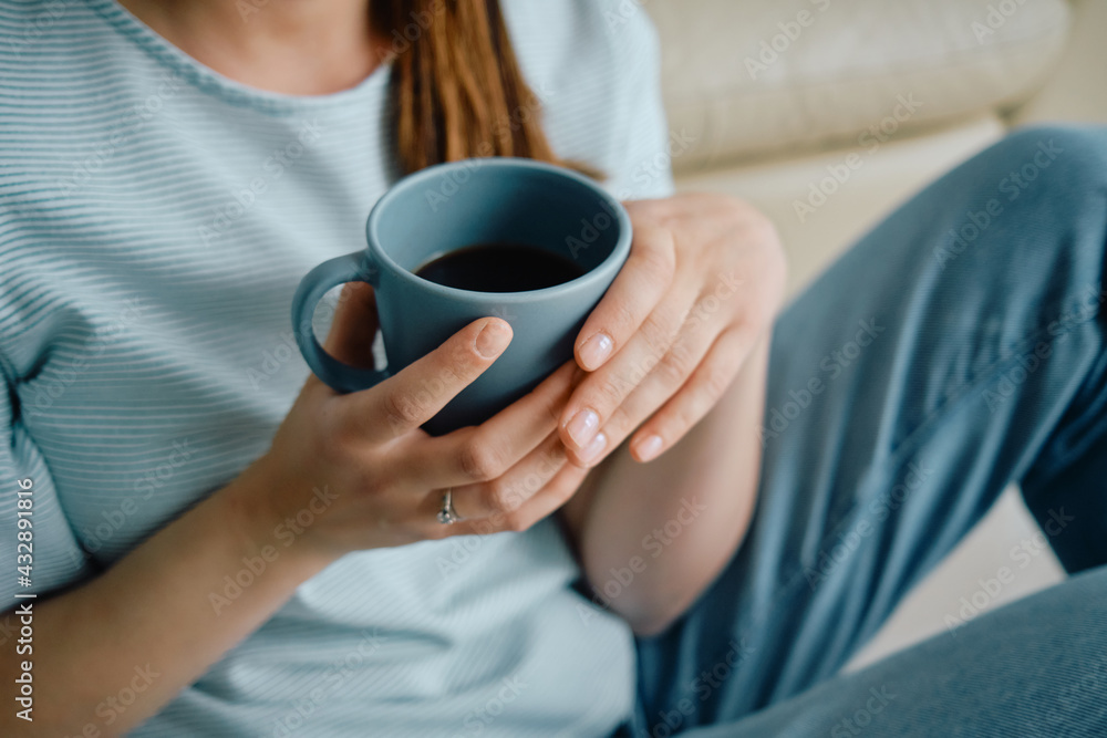 Close-up of woman having cup of coffee while relaxing at home. Close-up of woman having cup of coffee while relaxing at home.