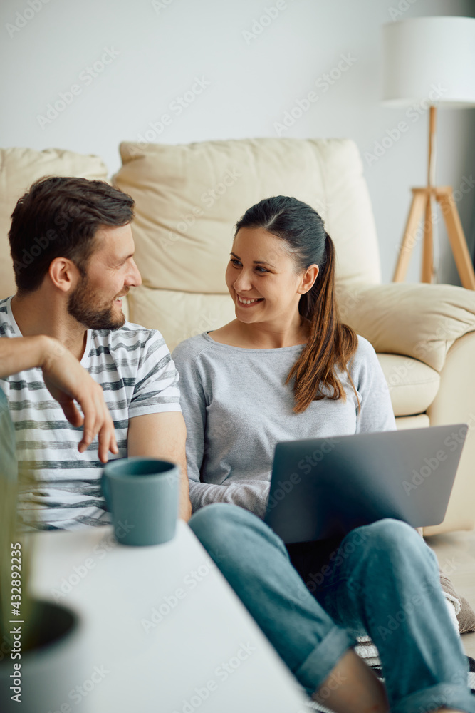 Happy couple talking while using laptop and relaxing in the living room. Happy couple talking while using laptop and relaxing in the living room.
