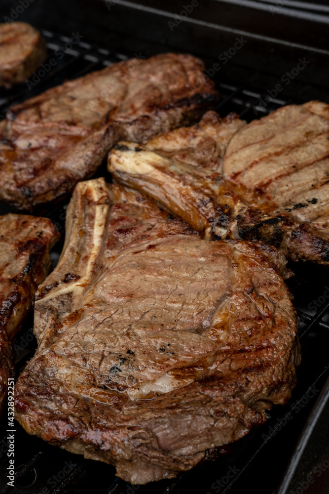 Steaks cooing over a flame grill, ready to be served. Shot shallow depth of field. Steaks cooing over a flame grill, ready to be served. Shot shallow depth of field.