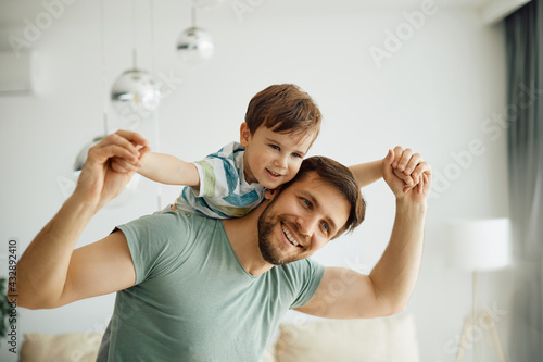 Happy father having fun while playing with his small son at home.