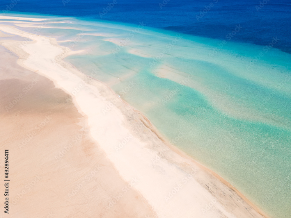 White sand beach with turquoise water background. Aerial drone shot.