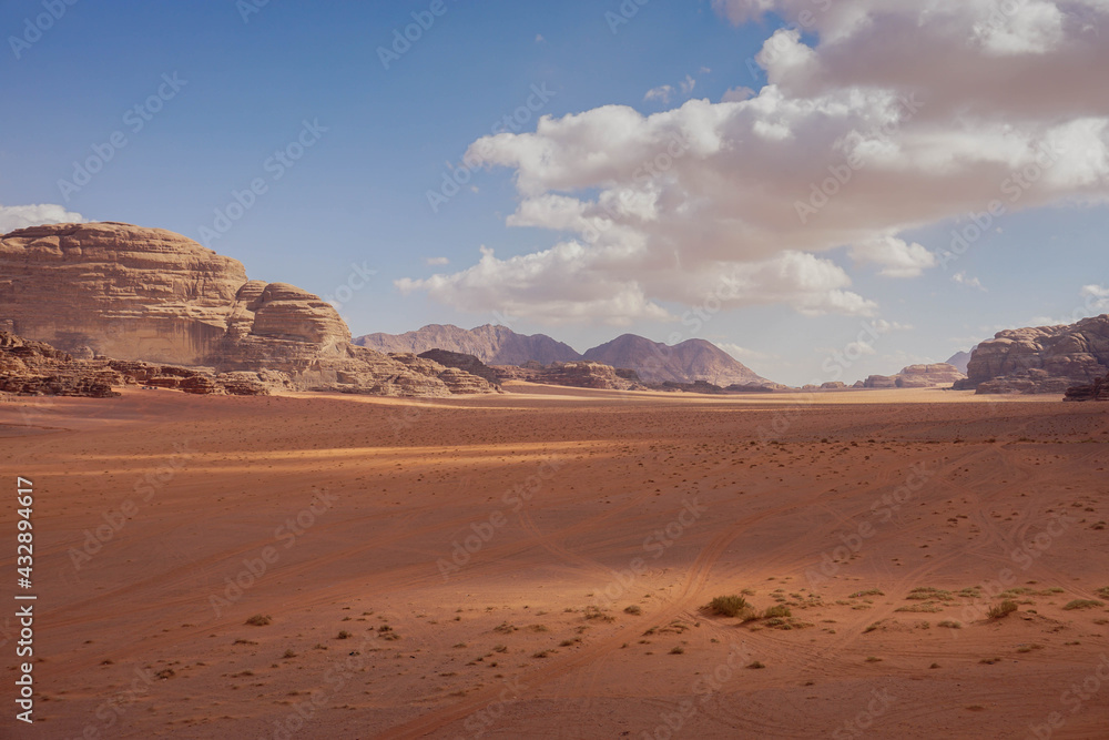 red desert of wadi rum with car tracks in the sand, cloudy weather, beautiful contrasting shadows, nature of Jordan