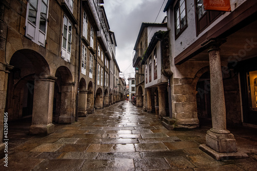 Fototapeta Naklejka Na Ścianę i Meble -  Santiago de Compostela - October 2018: Narrow street with porticoes in Santiago de Compostela on a rainy day