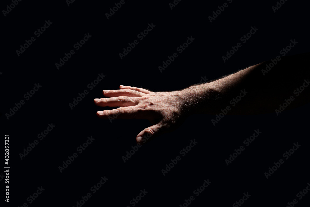 Light shining on a male hand in total darkness 