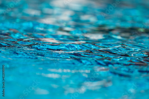 Background of waves, reflections, refractions and abstract diffractions, in the blue, clean and crystalline water of a swimming pool in the municipality of Gallur, Aragon, Spain, on a summer day. © Alvaro