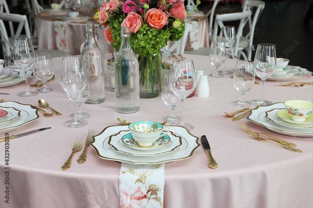 Fototapeta premium Table set up for bridal shower on bright summer day with flowers and vintage tea cups on each plate