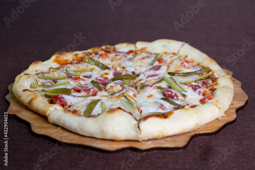 pizza with smoked sausage and cucumber on the stand