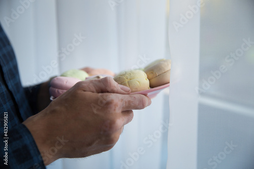 hands of a man with vitiligo in a blue shirt holding a macaroon photo from the top