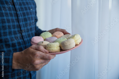 the hands of a man in a blue shirt are holding macaroons