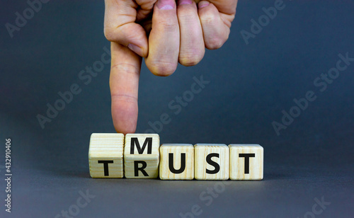 Must trust symbol. Businessman turns wooden cubes with words 'must trust'. Beautiful grey table, grey background. Business and must trust concept, copy space.