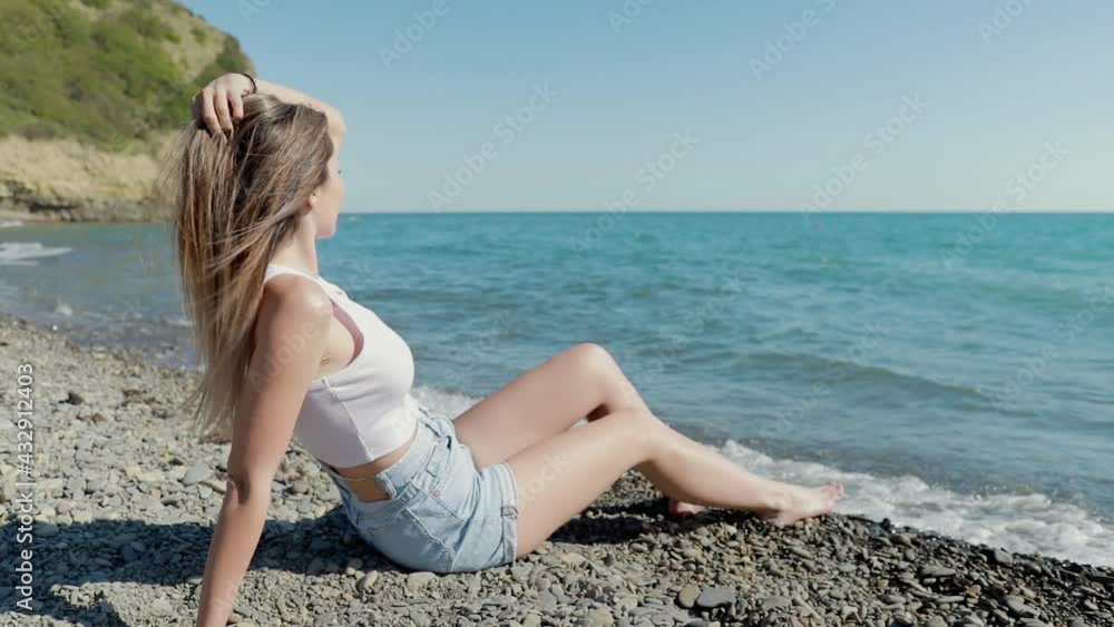 tourist caucasian woman sitting on the beach looking at the surf of the waves Amazing view of the turquoise water .summer vacation .stunning people tourist caucasian woman sitting on the beach looking at the surf of the waves Amazing view of the turquoise water .summer vacation .stunning people