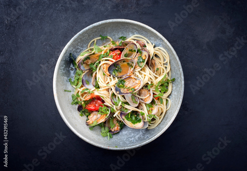 Spaghetti alle vongole with tomato in seafood jus served as top view at a Nordic design bowl with copy space photo