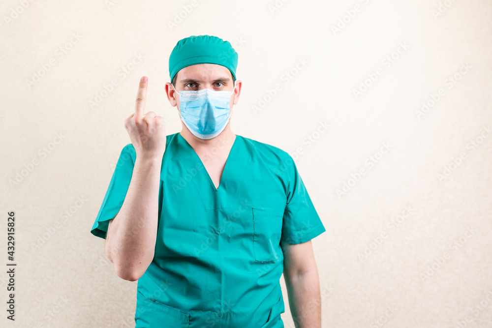 A doctor in a mask and a cap, shows an indecent gesture. A doctor in a mask and a cap, shows an indecent gesture.